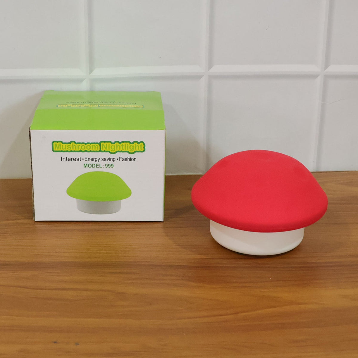 Red and white mushroom night light next to its green-themed product box on a wooden surface.