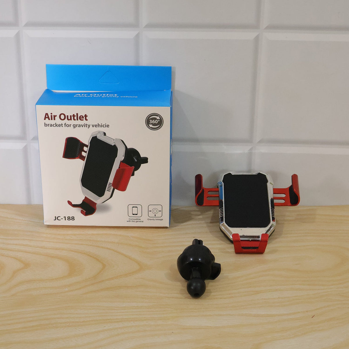 A red and silver car phone holder and its attachment sit next to a blue and white product box.