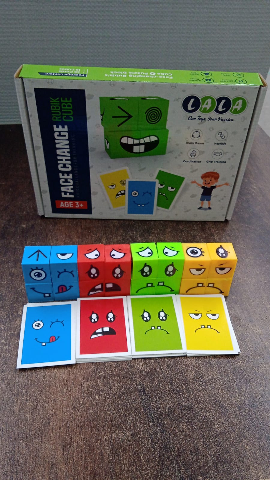 A product box for a "Face Change Rubik Cube" is shown with a line of colorful emotion cubes and matching cards below it.