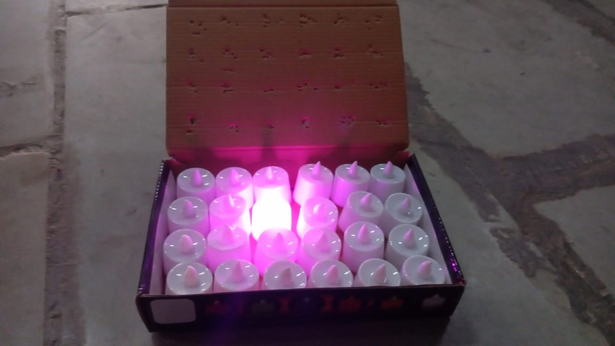 An open cardboard box filled with white LED tealights, with one glowing pink in the center.