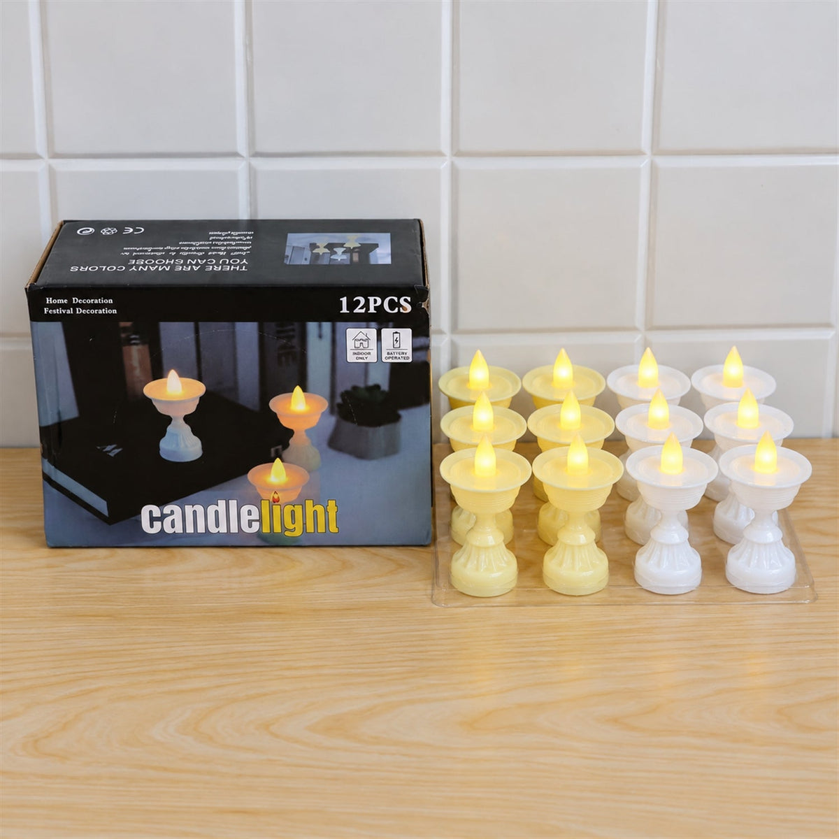 A black box labeled "candlelight" sits next to twelve LED diya candles, six yellow and six white, on a light wooden surface.