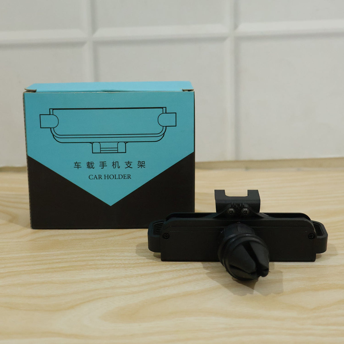 A black car phone holder next to its blue and black packaging box on a wooden surface.