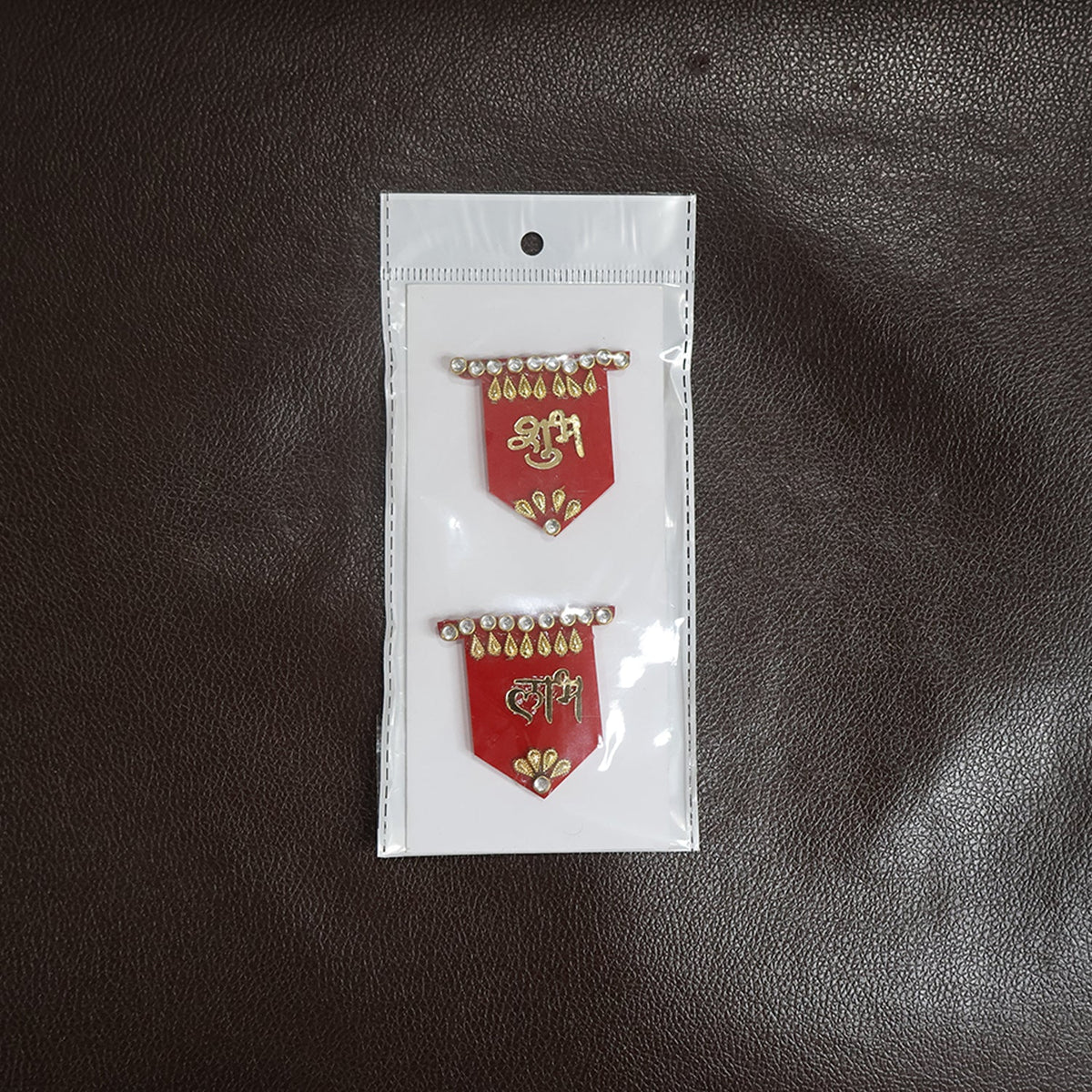 Two red Shubh Labh wall hangings with gold and clear stone embellishments, sealed in clear plastic packaging with a white