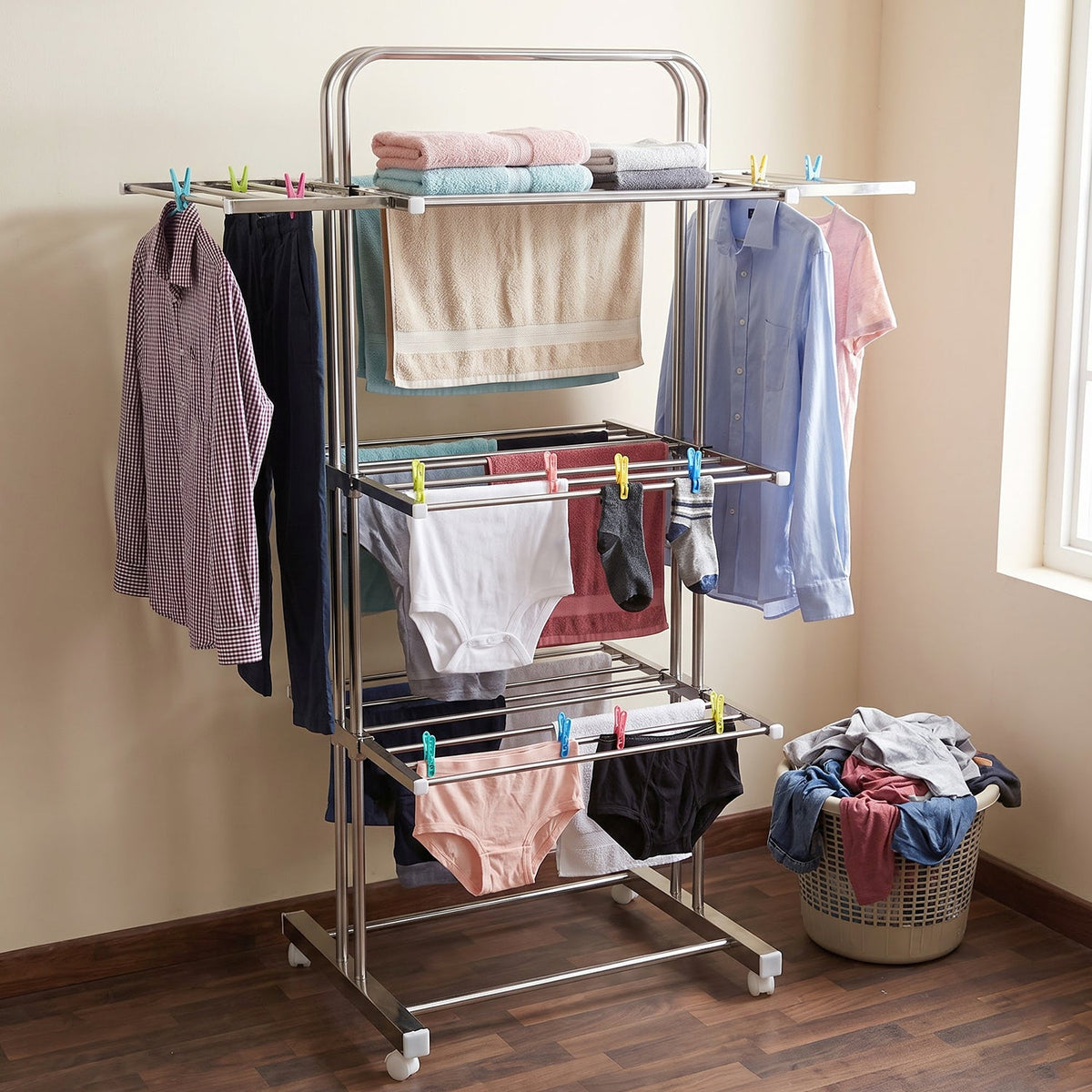 A stainless steel 3-layer clothes drying rack with various clothing items, including shirts, towels, and underwear,