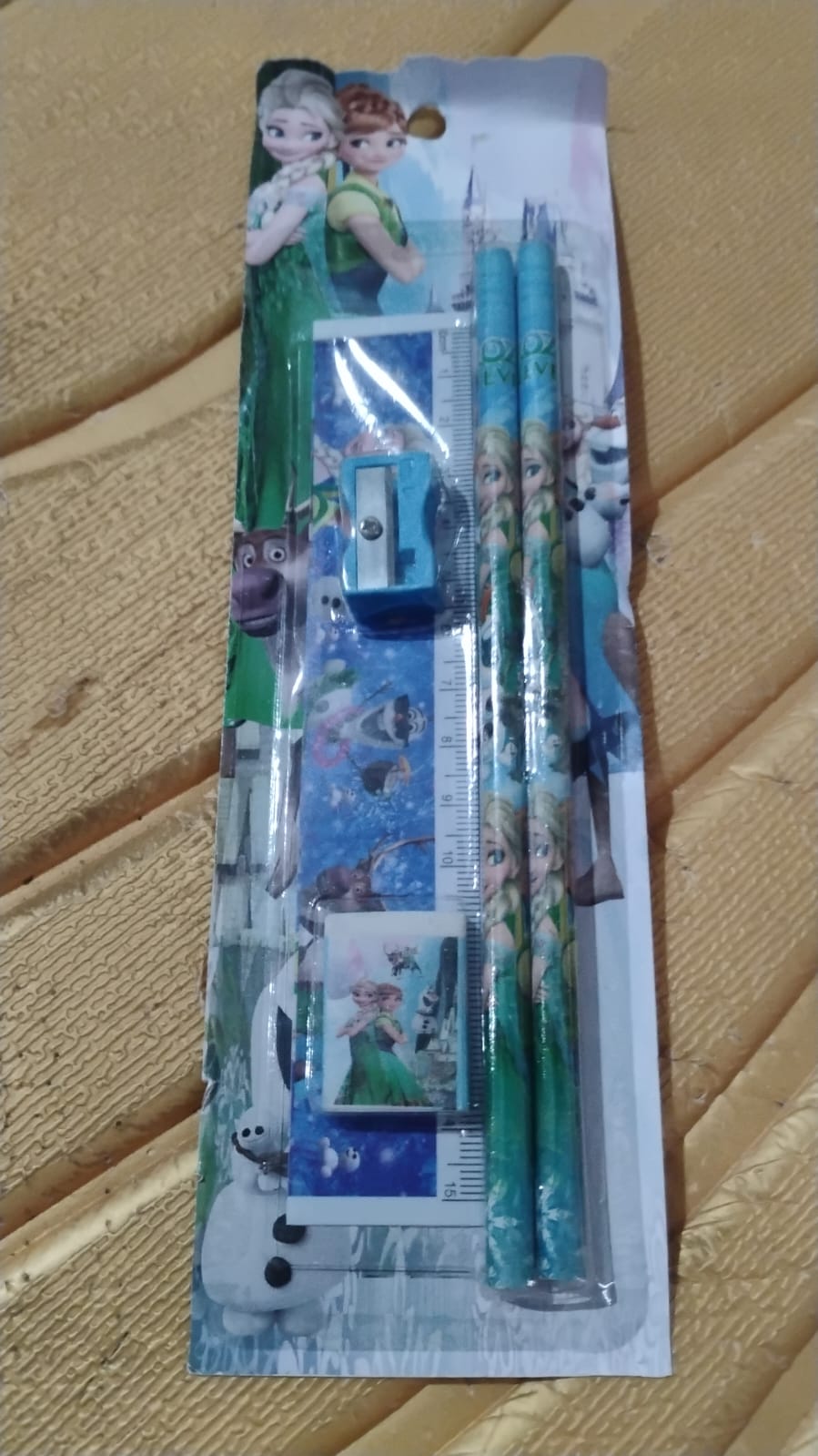 A packaged 5-piece Frozen-themed stationery set on a textured brown surface.