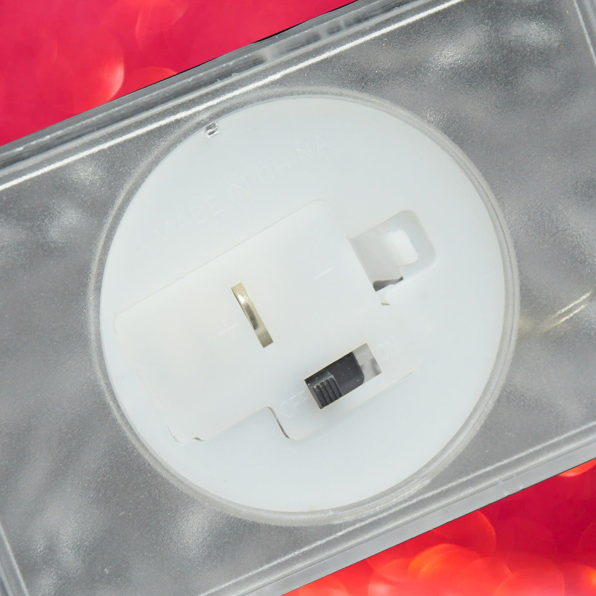 A close-up of the bottom of the clear LED iceberg light reveals a white battery compartment with an on/off switch.
