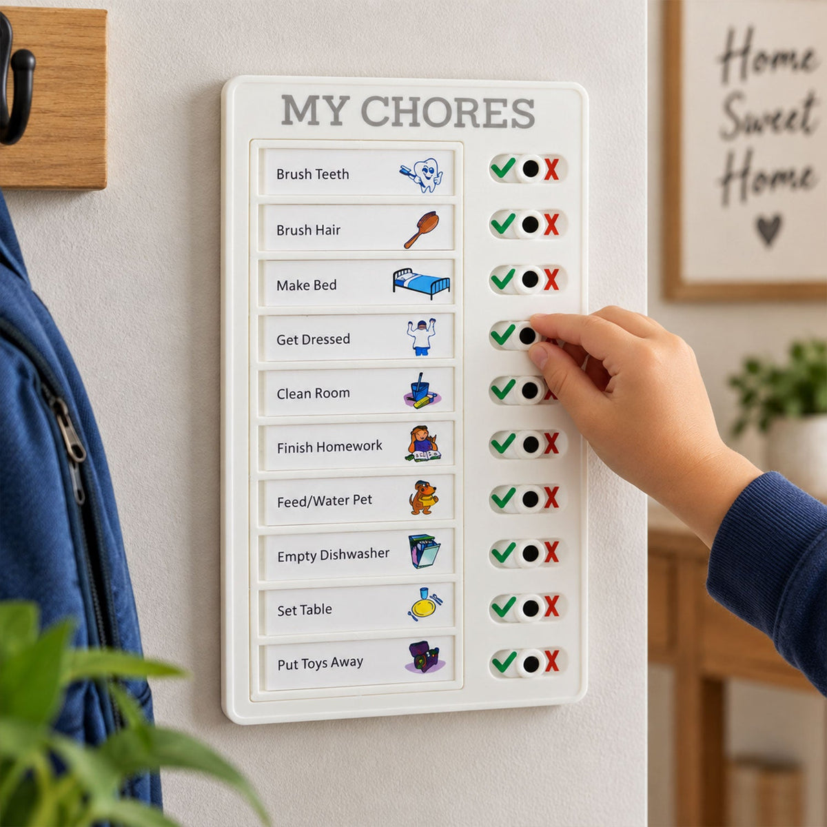 A child's hand slides a black knob on a white chore board to mark a task complete.