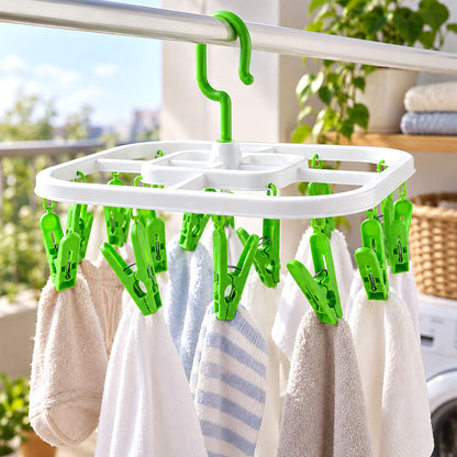 White square drying rack with green clips holding small towels on a balcony clothesline.
