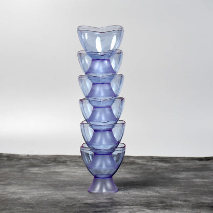 A stack of six translucent blue plastic ice cream bowls on a dark grey surface against a light grey background.