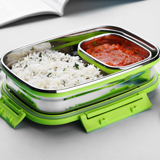 An open stainless steel lunch box with a bright green base, containing white rice and a small container of red curry.