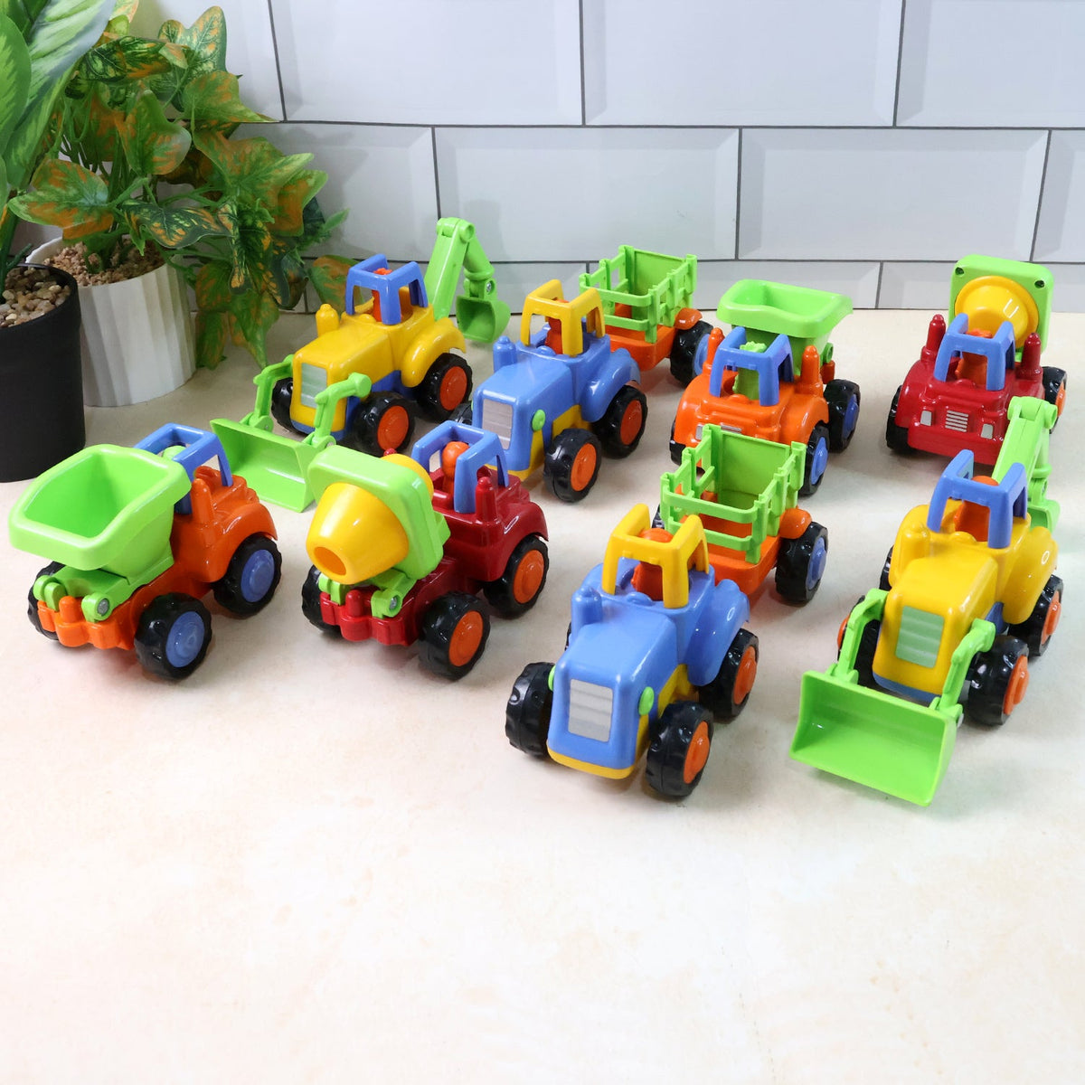 Eight colorful plastic construction vehicle toys arranged on a white surface against a tiled background.