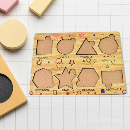 The empty wooden shape sorting puzzle board rests on a white grid surface, surrounded by other wooden blocks.