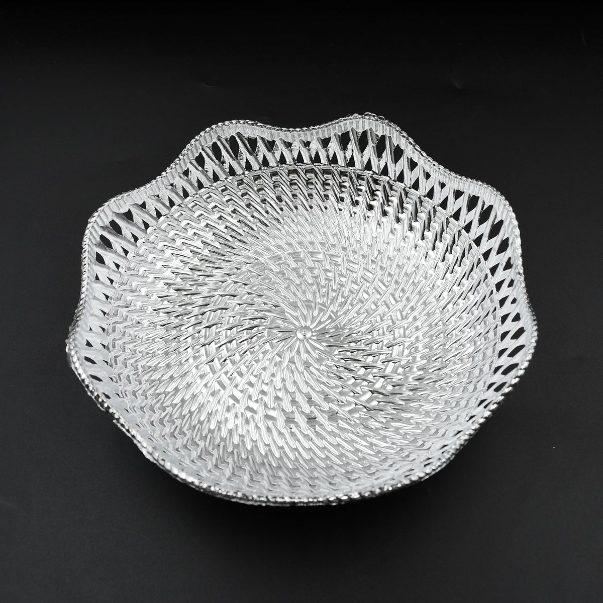 A silver plastic scalloped serving bowl with a textured bottom is centered on a black background.