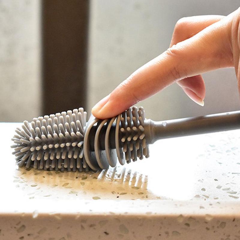 A close-up of a finger touching the grey silicone bristles of the brush head.