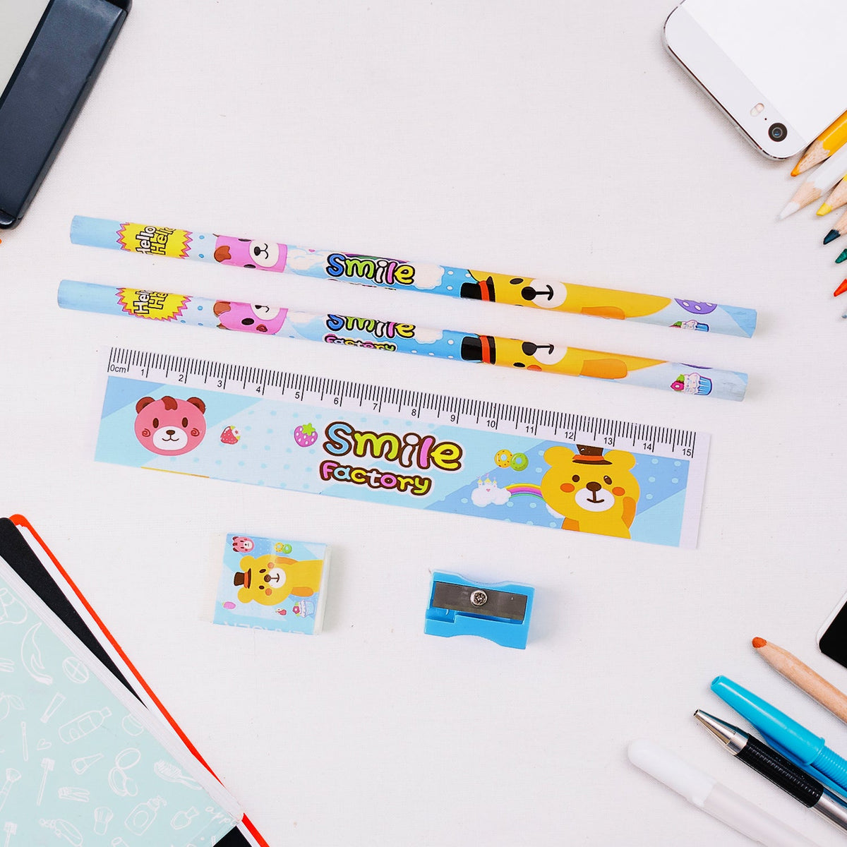 A 5-piece cartoon bear stationery set on a white desk with a phone and other stationery items.