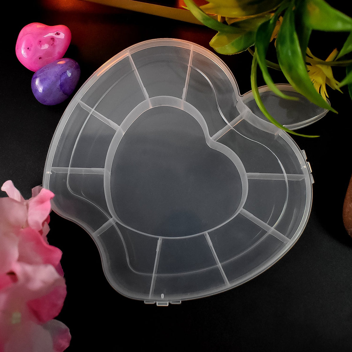 A transparent apple-shaped organizer box with a heart-shaped center is displayed with its lid slightly open, surrounded by