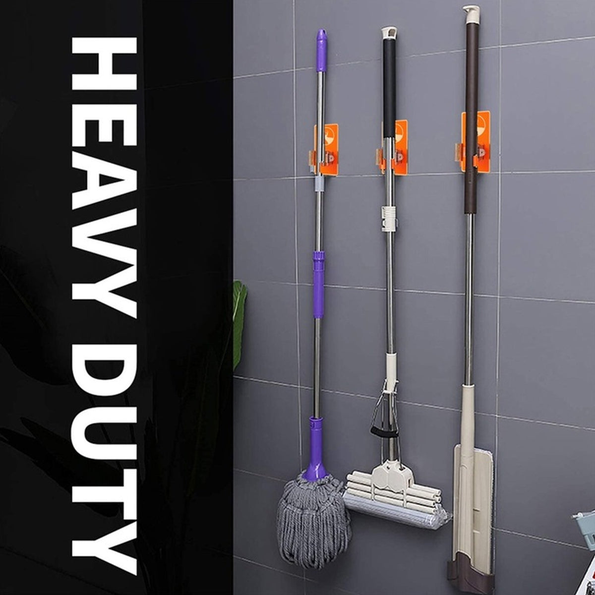 Three different mops and brooms hanging from orange deer-themed wall-mounted holders on a dark grey tiled wall.