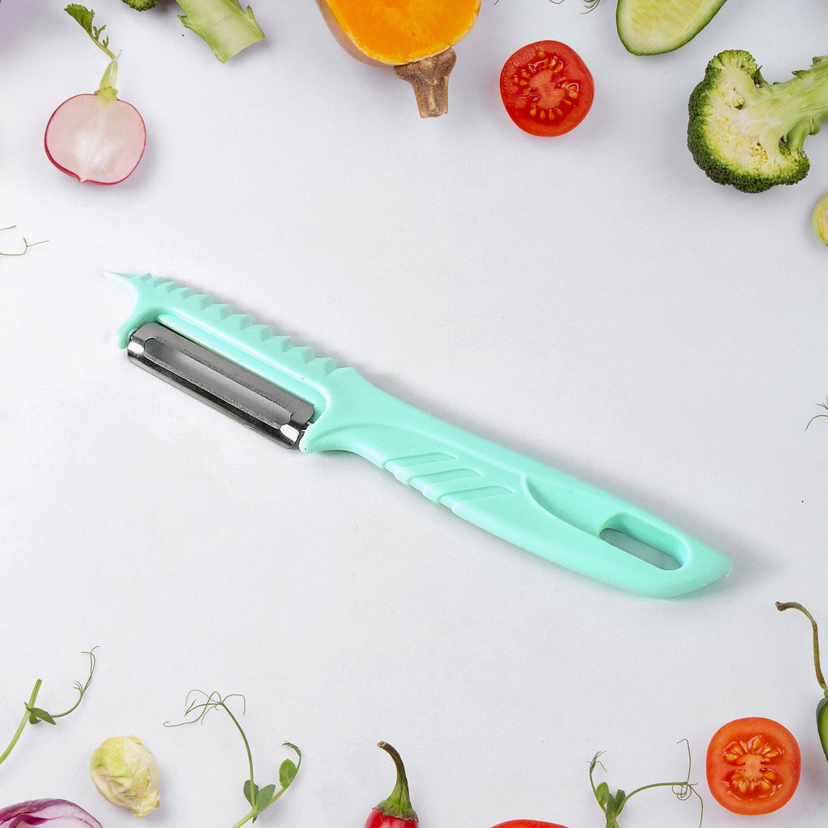 A teal vegetable peeler with a serrated edge and a stainless steel blade, surrounded by various vegetables.