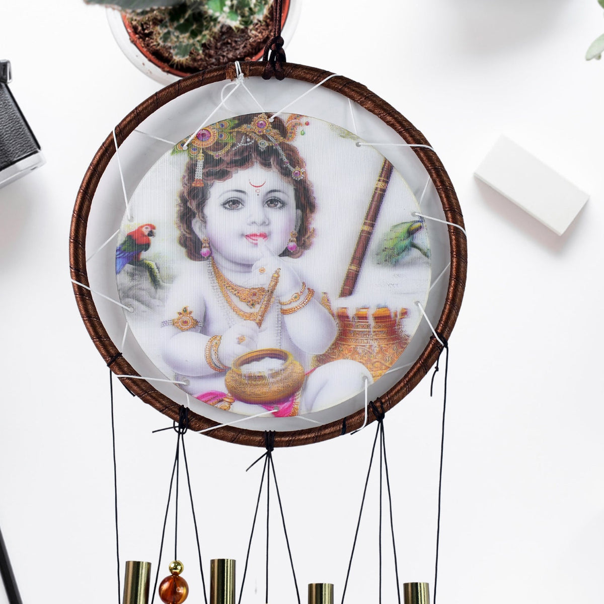 A close-up of the Krishna medallion on the wind chime, showing baby Krishna with a pot of butter.