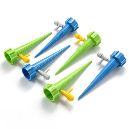 Six watering spikes, three blue and three green, arranged on a white surface.