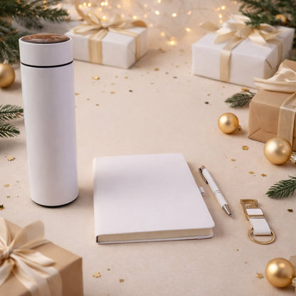 White thermal bottle, notebook, pen, and keychain on a light surface with blurred festive gifts and lights.