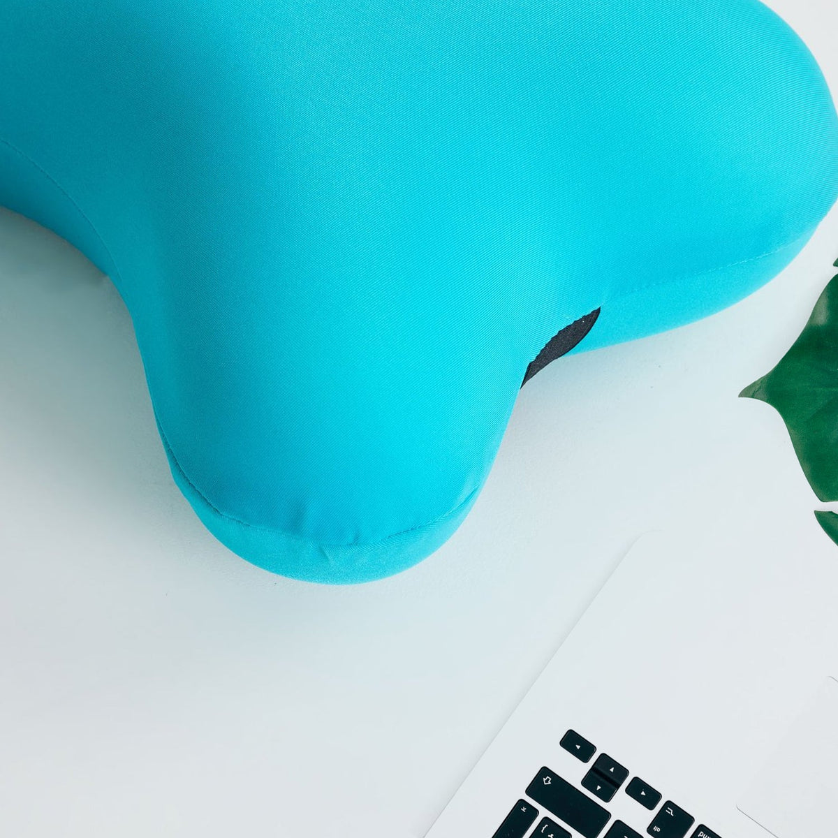 Two blue microbead pillows, one bone-shaped and one cylindrical, above a woman sleeping with a blue pillow.