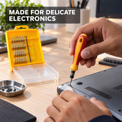 A person uses a yellow and red screwdriver from a 32-piece set to repair delicate electronics on a wooden desk.