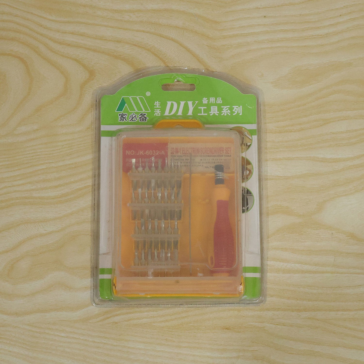 A 32-in-1 precision screwdriver set in its clear retail packaging with green and orange accents, on a wooden surface.