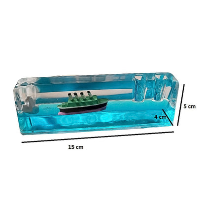 A clear rectangular liquid motion paperweight with a green ship and iceberg floats in blue liquid, showing dimensions of