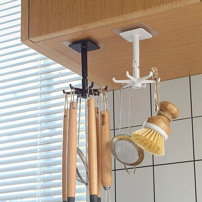 Two rotating hooks, one black and one white, hang from a wooden cabinet, holding various kitchen utensils.