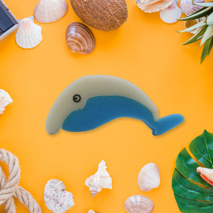 The blue and white dolphin sponge is centered on a yellow background, surrounded by seashells and tropical decor.
