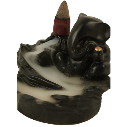 Close-up side view of the black Ganesha smoke fountain with a lit incense cone and smoke cascading downwards.