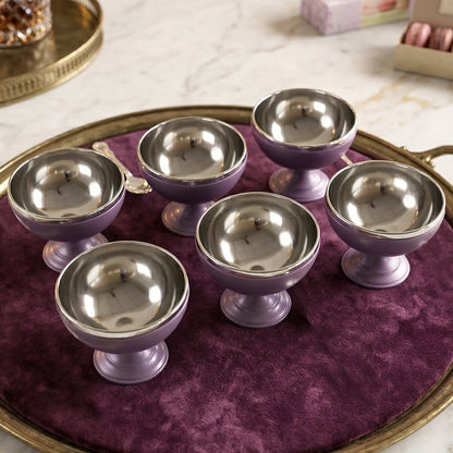 Six purple and silver dessert bowls are neatly arranged on a round, gold-rimmed tray with a velvet surface.