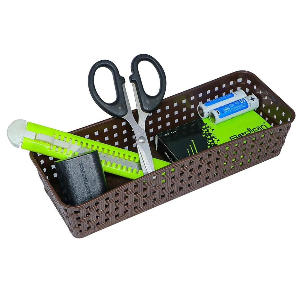 A brown rectangular plastic basket filled with scissors, a cutter, and batteries on a white background.