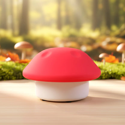 Red and white mushroom night light on a wooden table with a blurred forest background.