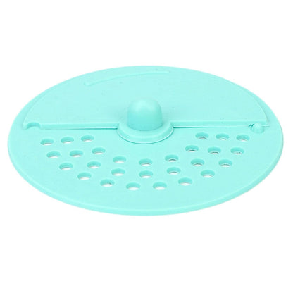 A light green silicone drain strainer with a central knob and two sections of holes is shown from above.