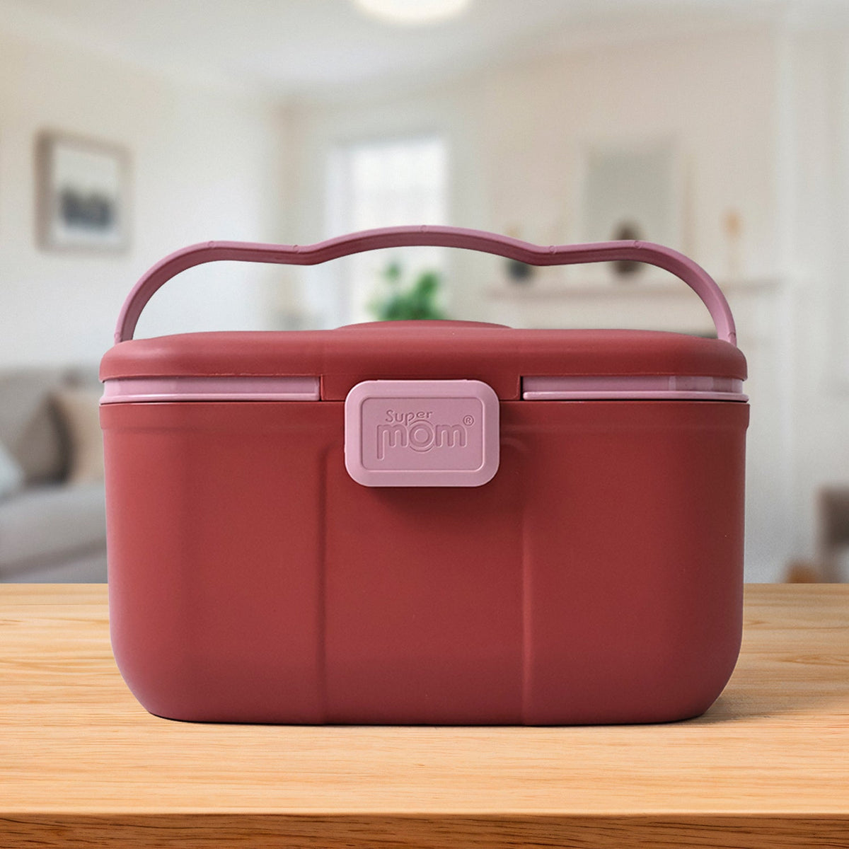 Closed red and pink plastic storage box with a wavy pink handle and 'Super Mom' clasp, on a wooden table in a room.