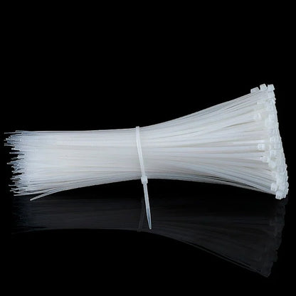 A large bundle of white cable ties, secured together, lying on a reflective black surface.