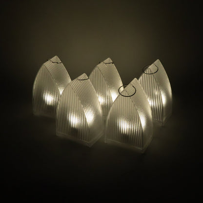 Five clear plastic ribbed lanterns with warm LED lights glowing in a dark setting.