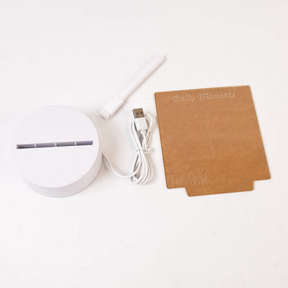 The lamp components laid out: a white circular base, a USB cord, a white marker, and a rectangular brown acrylic board.