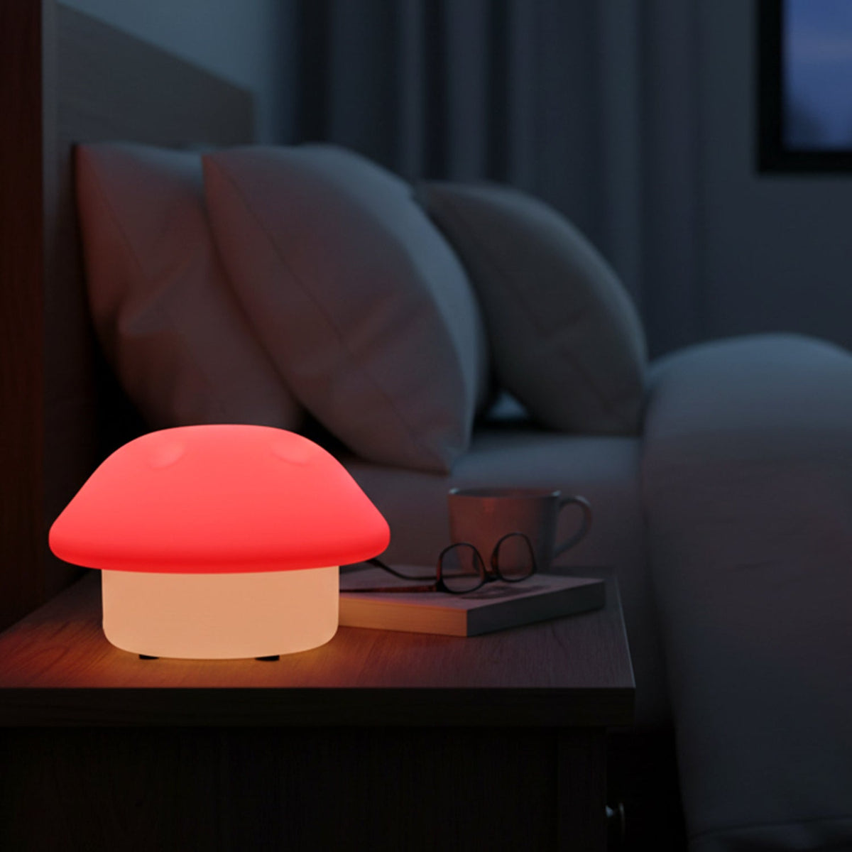 Glowing mushroom night light on a dark wooden bedside table next to a bed with white pillows.