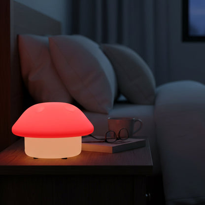 Glowing mushroom night light on a dark wooden bedside table next to a bed with white pillows.