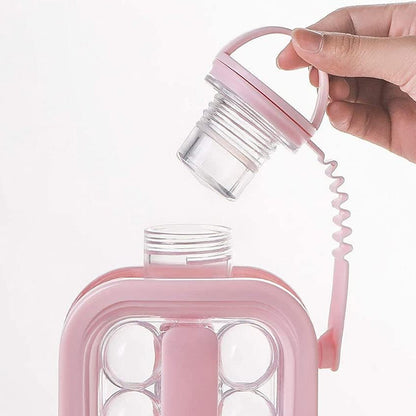 A hand holds the pink screw-top lid of an ice ball maker bottle, revealing the threaded opening and clear interior.