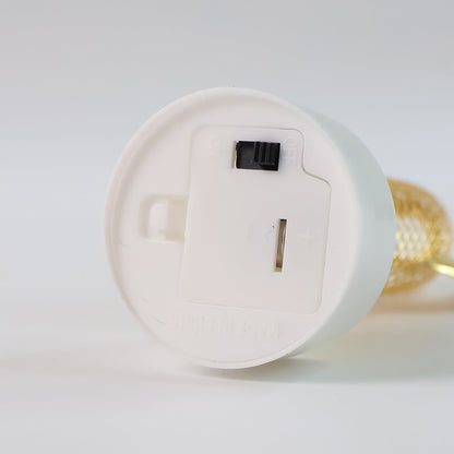 The underside of a white light base shows a battery compartment with an open lid and a black on/off switch.