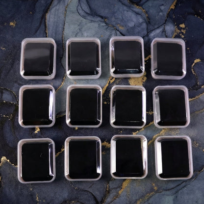 Twelve clear-lidded white jewellery boxes with black inserts arranged on a dark blue and gold marbled surface.