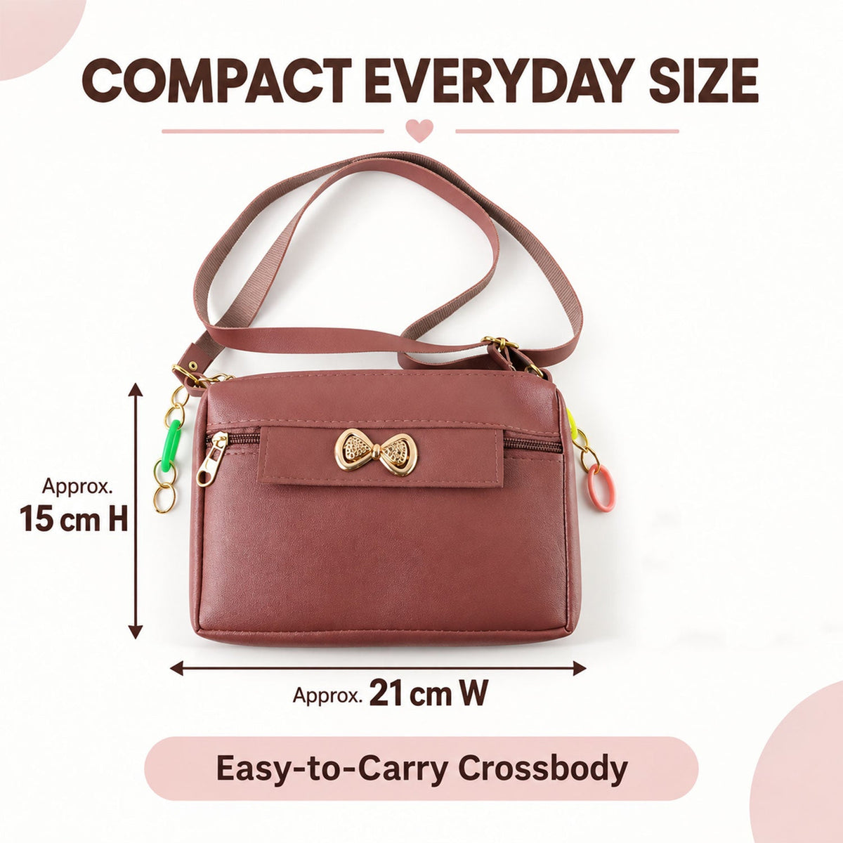 A mauve sling bag with a gold bow and colorful charms, showing approximate dimensions of 15cm H x 21cm W.