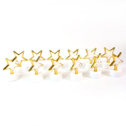 Twelve unlit star-shaped LED candles with gold frames and white bases lined up on a plain white background.