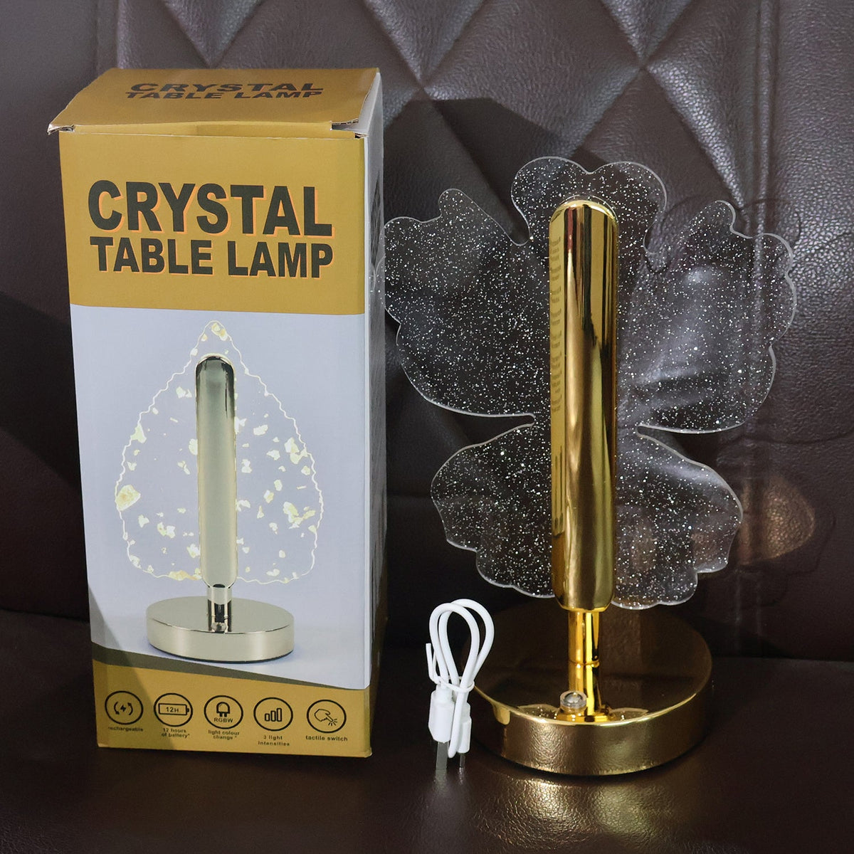 A crystal butterfly-shaped table lamp and its product box, with a white USB cable, on a brown surface.