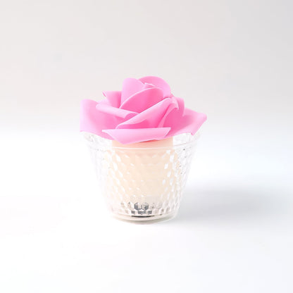 A single pink rose-shaped LED candle in a clear textured holder on a plain white background.
