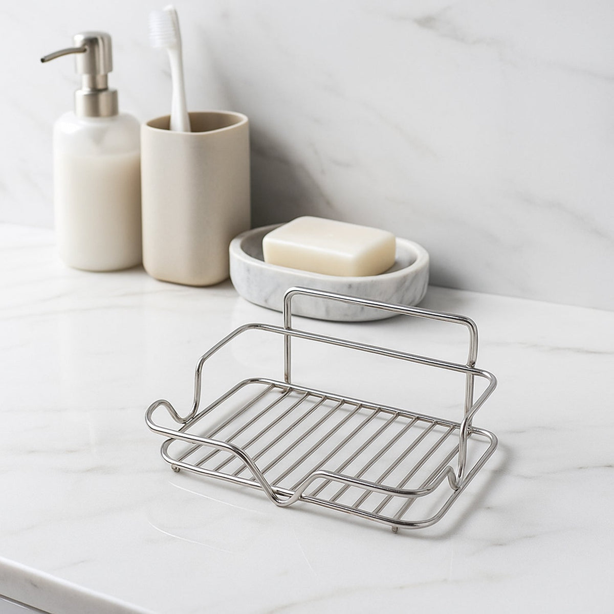 A stainless steel wire soap dish sits on a marble counter with a toothbrush holder and a soap dish with soap behind it.